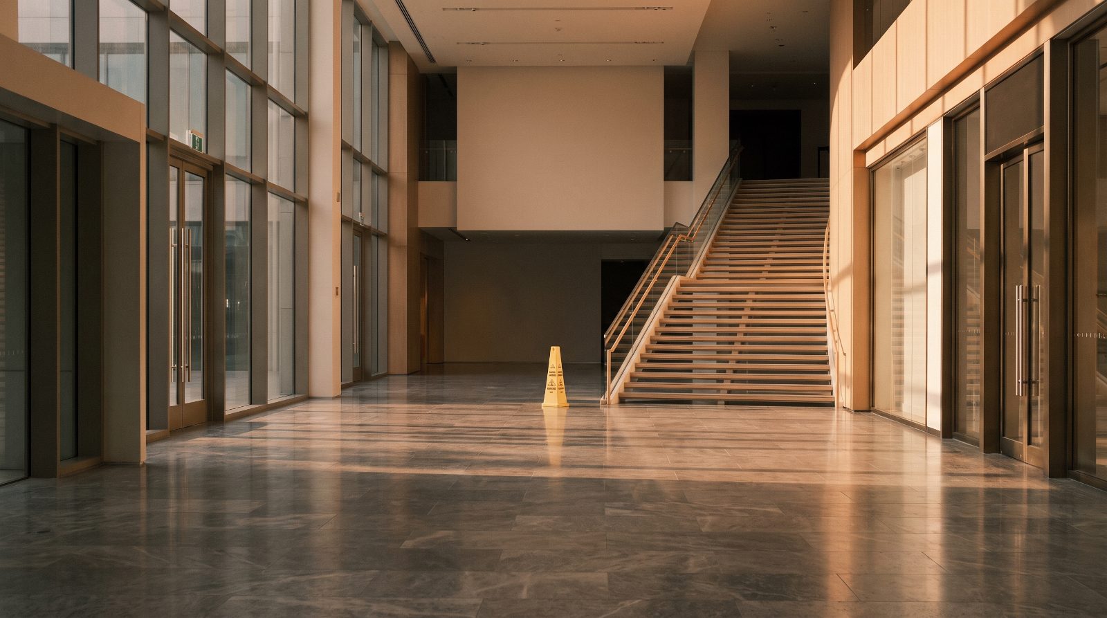 Wet floor caution cone in an empty retail atrium near a staircase